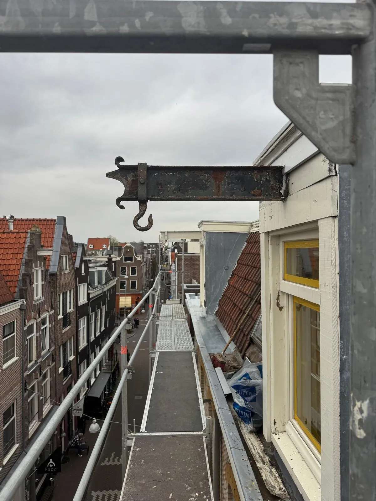 Hijsbalk naast een dakkapel met uitzicht over een Amsterdamse straat